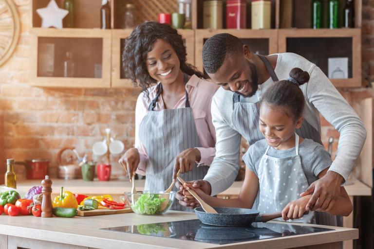 A young family enjoying their time in the kitchen with the right cooktop for their cooking activities.