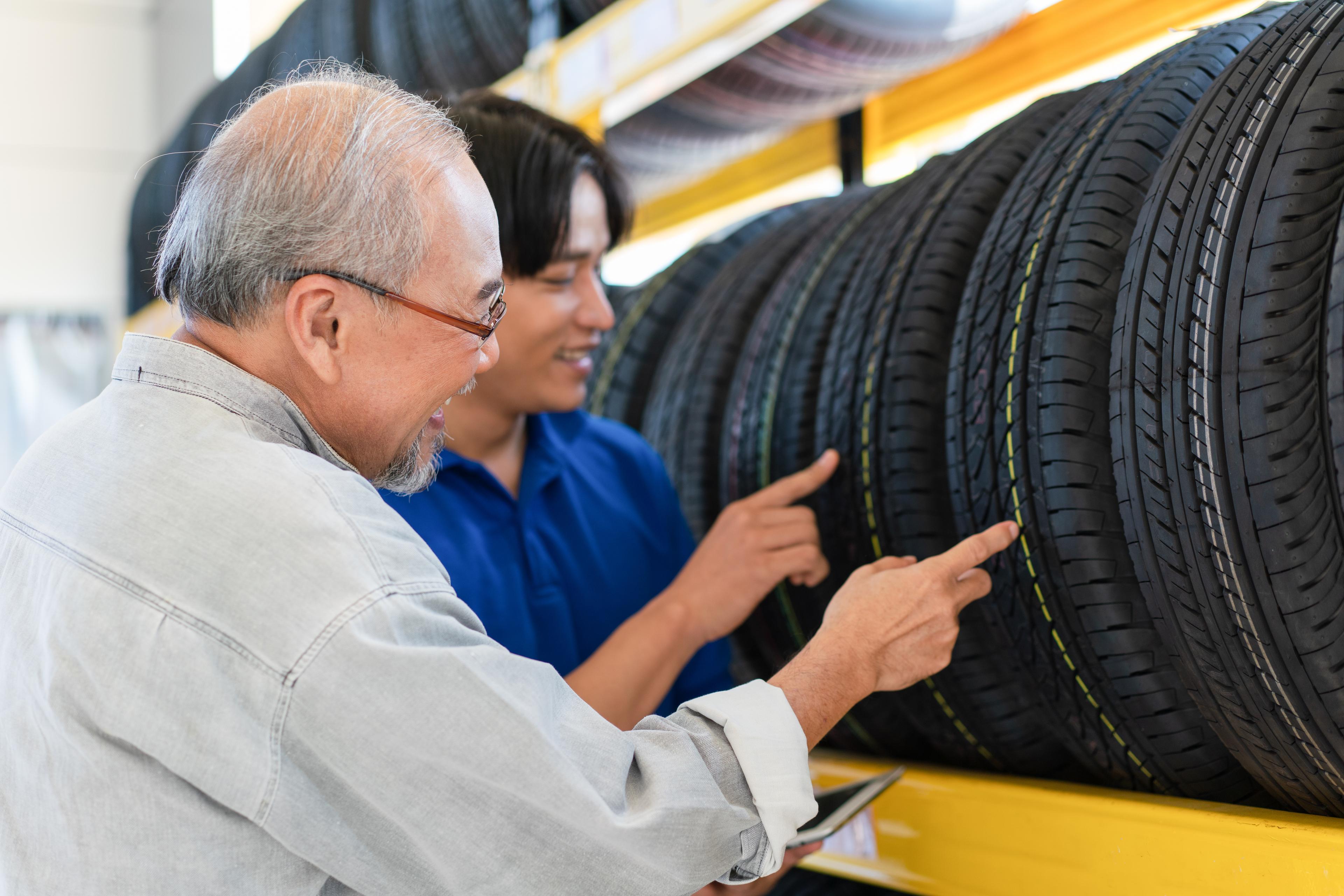 An employee showing a new potential customer their options while shopping for tires.