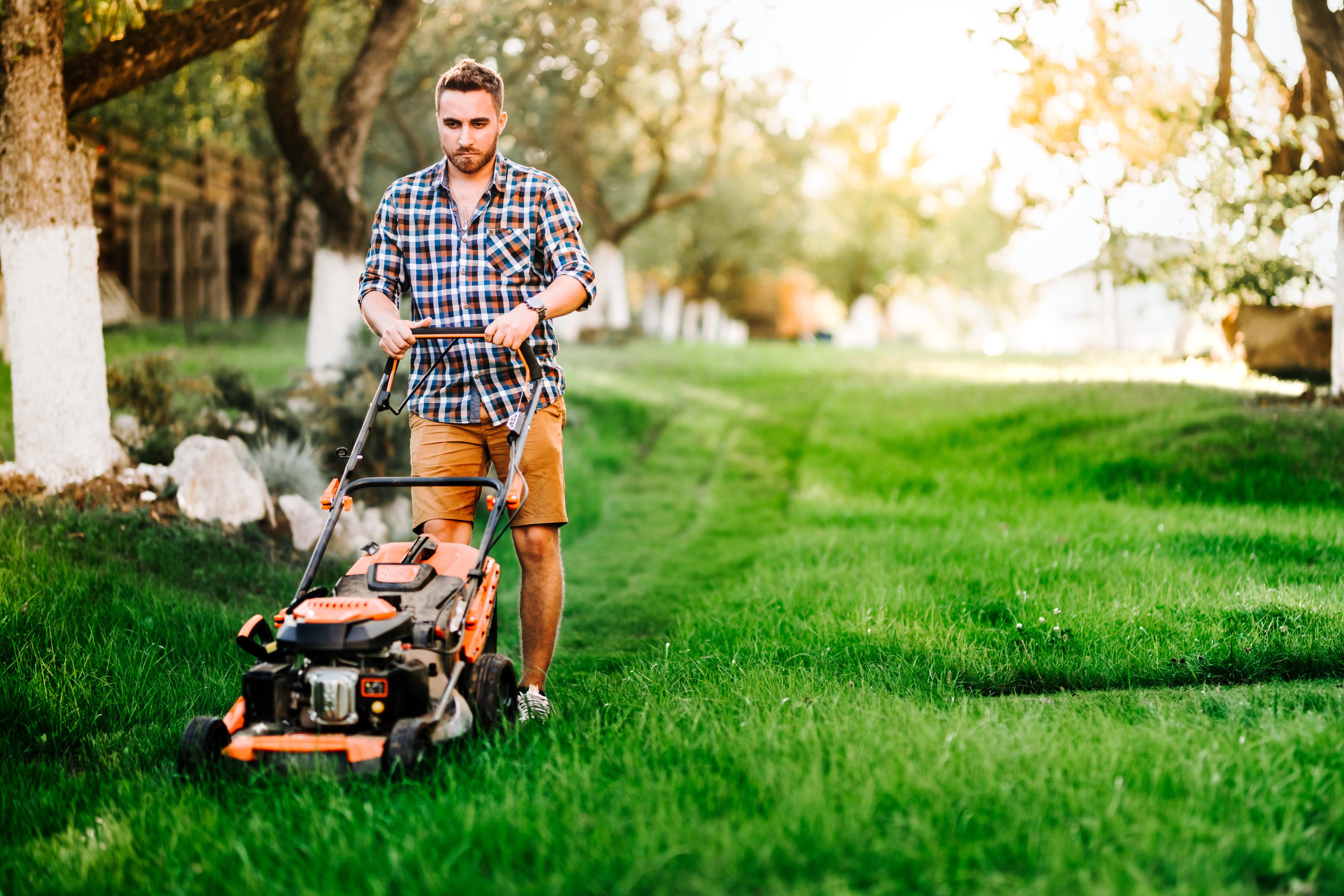 With a determined expression, a person mows their lawn, showcasing the satisfaction that comes from maintaining a well-groomed yard.