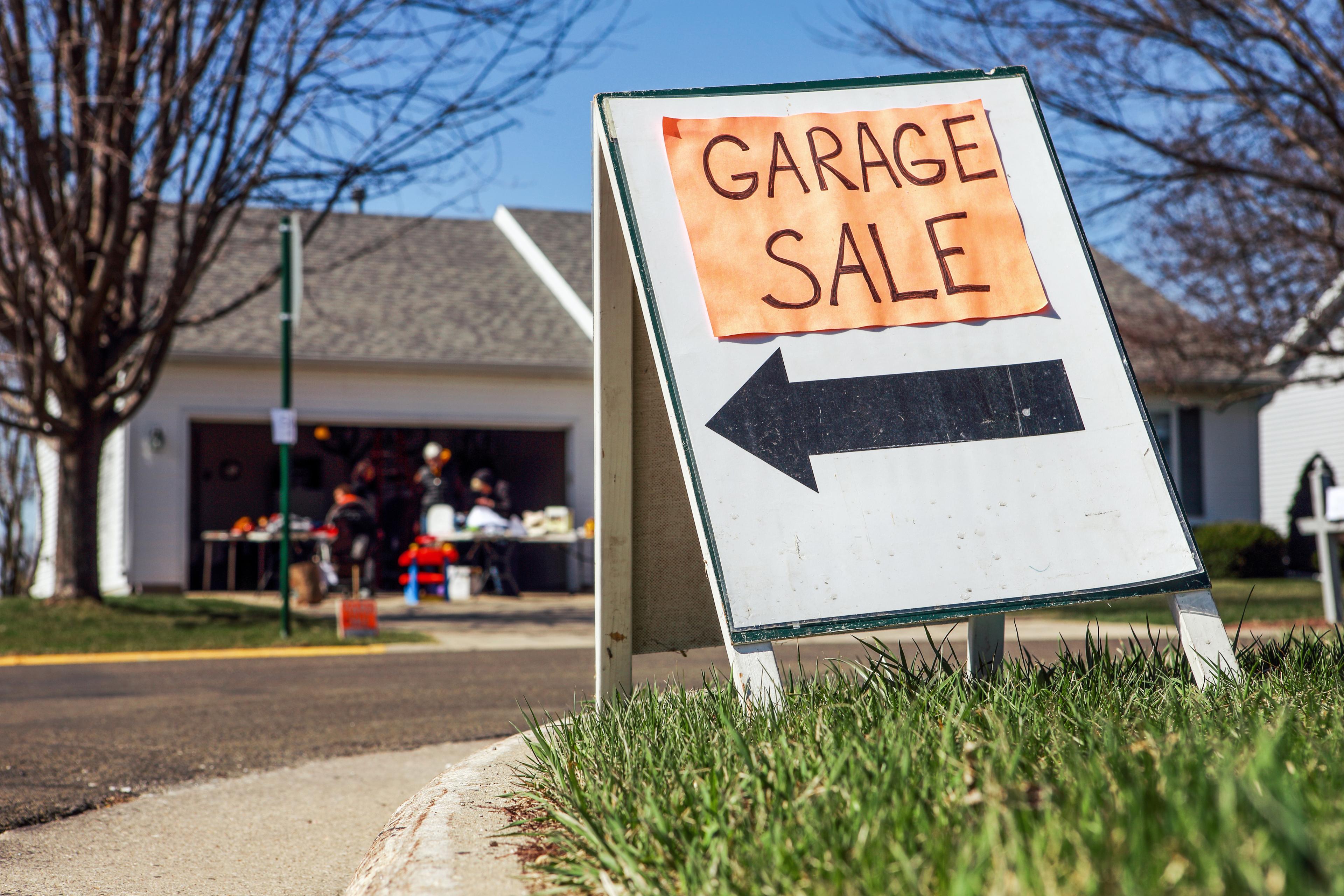 A view of a lawn set up for a garage sale where people are clearing space for new furniture, appliances, electronics and more household items.
