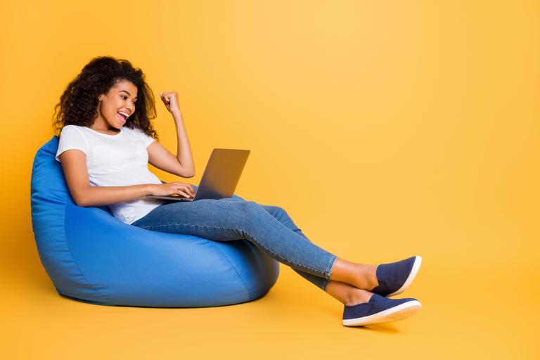 A girl looking at her laptop while sitting on a beanbag chair